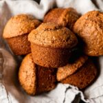 An overhead shot shows vegan bran muffins nestled into a linen-lined bowl.